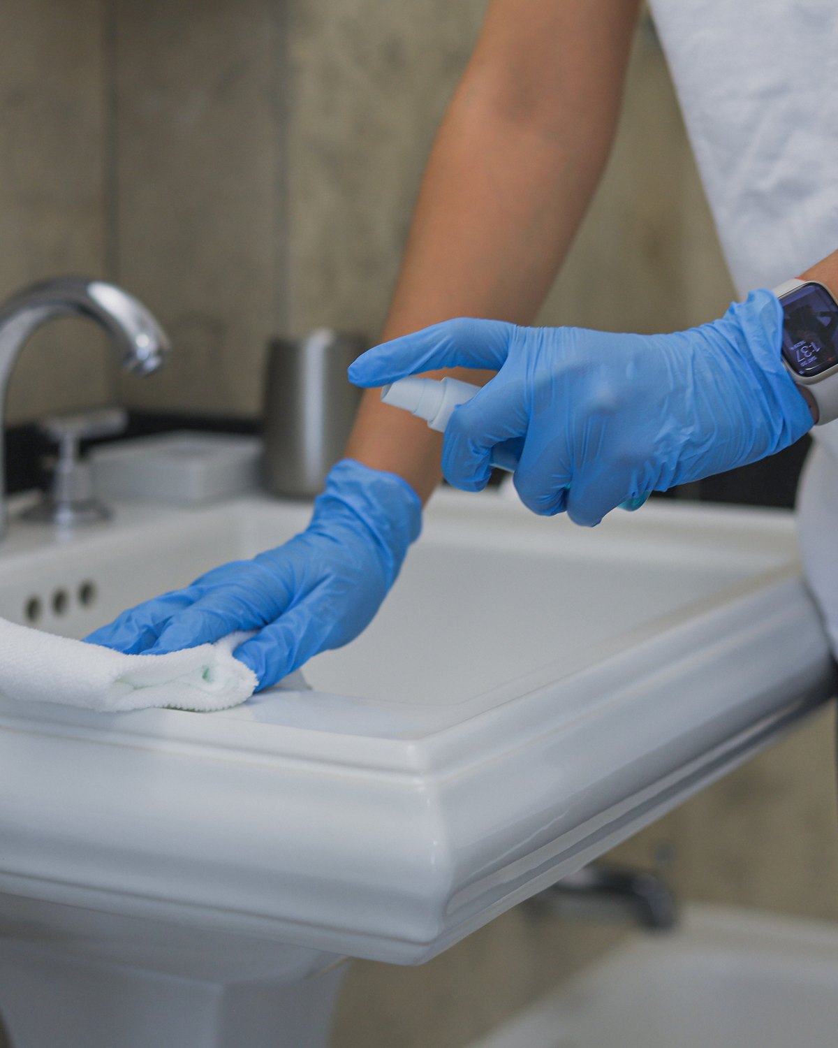 Gloved Cleaning Master professional disinfecting a bathroom sink