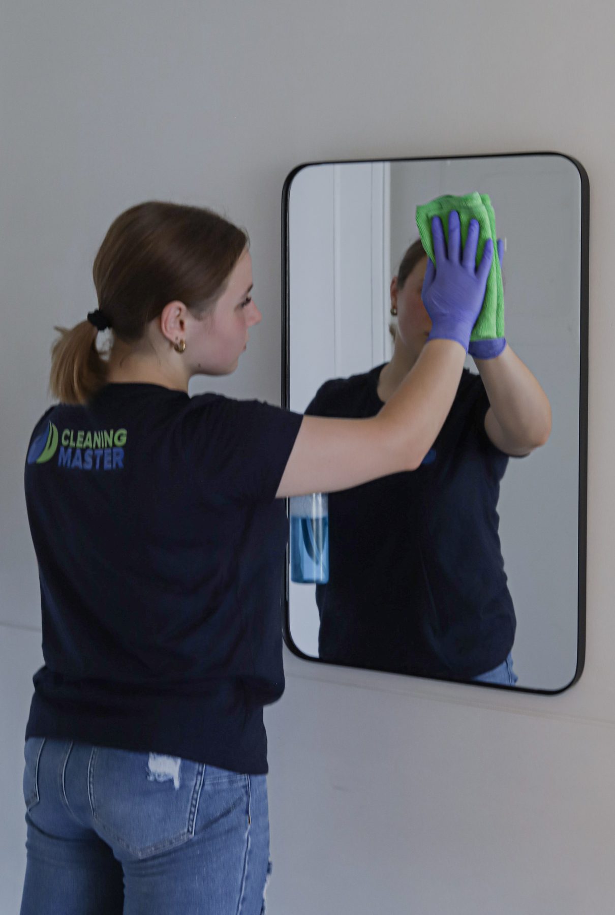 Cleaning Master professional cleaning a wall mirror in a Queens home