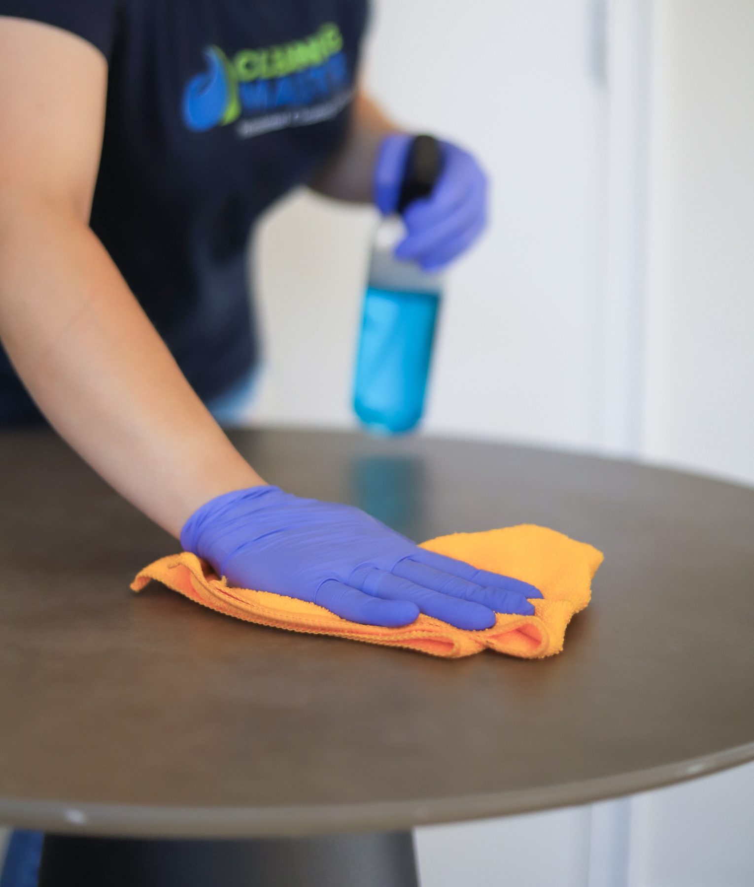 Cleaning Master professional sanitizing an office desk with spray and microfiber