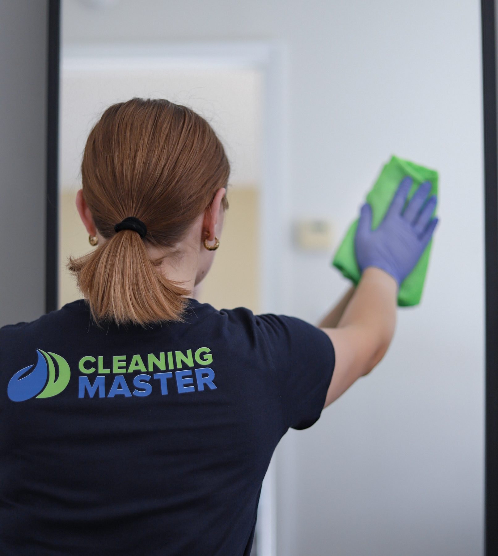 Cleaning Master professional in a branded team shirt cleaning an interior door