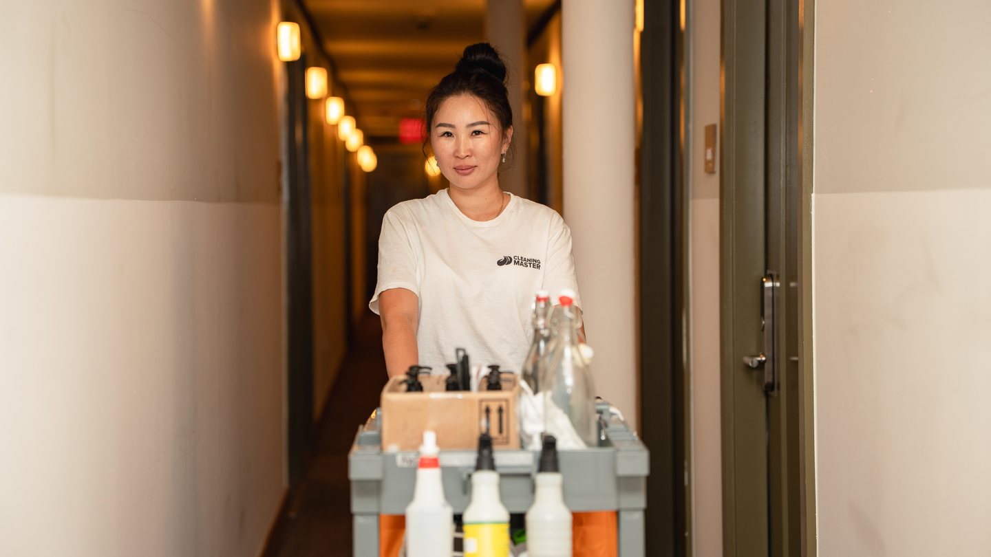 Cleaning Master professional pushing a housekeeping cart down a hotel corridor