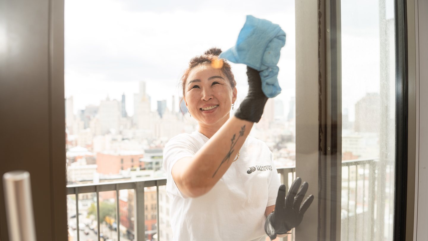 Smiling Cleaning Master professional cleaning glass with the Manhattan skyline behind