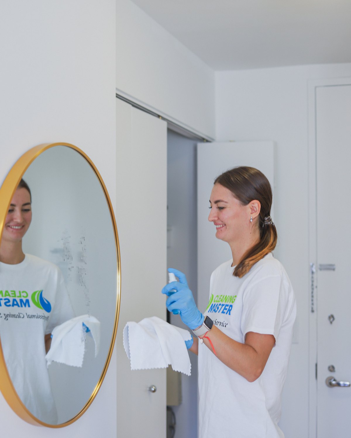 Smiling Cleaning Master professional polishing a round mirror in a New York apartment